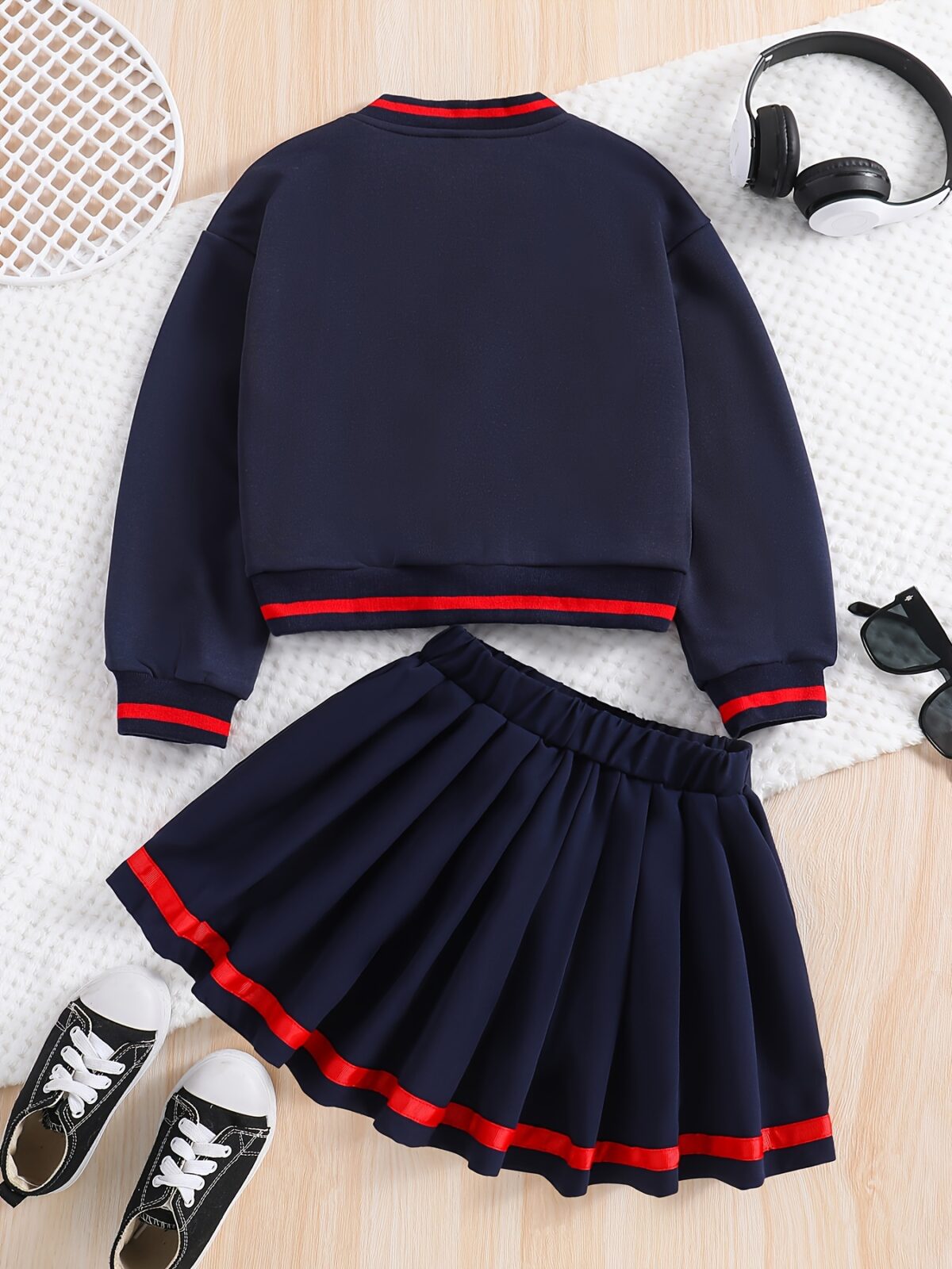 Stylish preppy varsity jacket and skirt set in navy and cream modeled on a student in a school setting