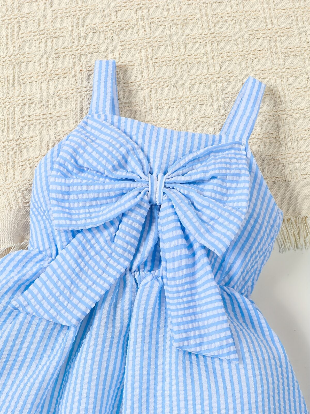 Adorable little girl wearing a stylish navy and white striped summer dress perfect for playdates and picnics She is smiling and looks happy