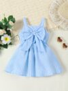 Adorable little girl wearing a stylish navy and white striped summer dress perfect for playdates and picnics She is smiling and looks happy