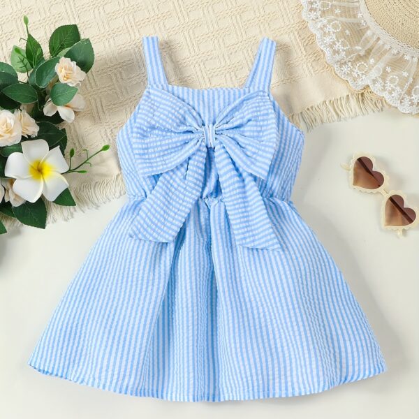 Adorable little girl wearing a stylish navy and white striped summer dress perfect for playdates and picnics She is smiling and looks happy