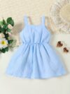 Adorable little girl wearing a stylish navy and white striped summer dress perfect for playdates and picnics She is smiling and looks happy