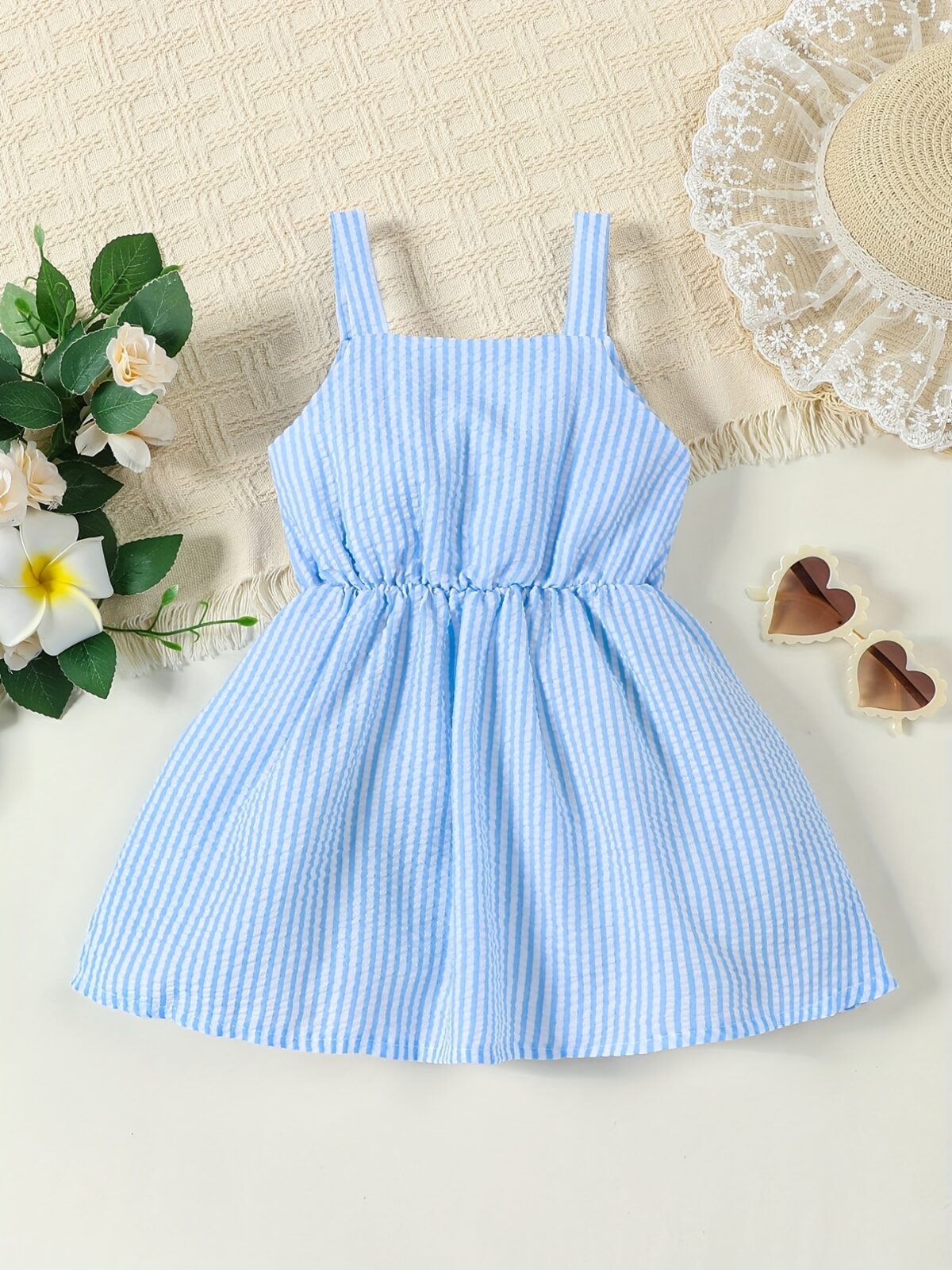 Adorable little girl wearing a stylish navy and white striped summer dress perfect for playdates and picnics She is smiling and looks happy