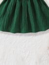 A baby girl wearing a charming summer garden themed dress smiling