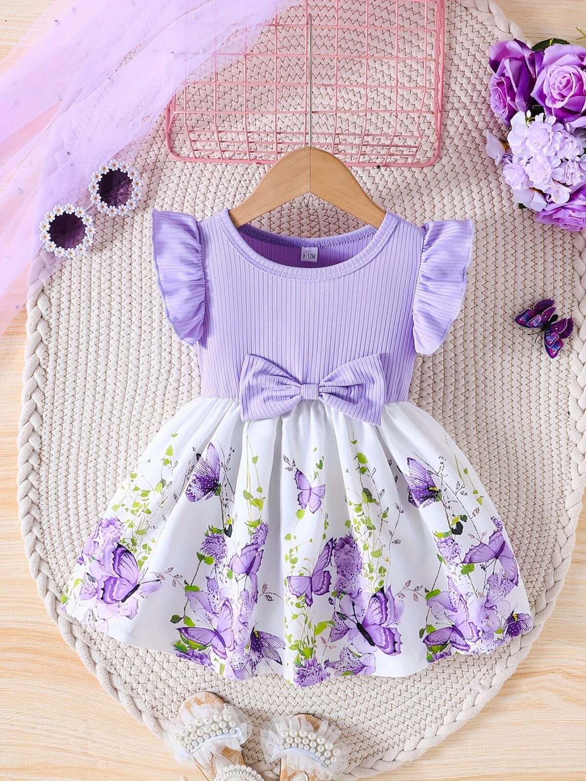 Adorable baby girl wearing a charming butterfly print dress from Newness perfect for spring and summer