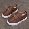 Close up of stylish brown leather boys loafers showcasing the stitching and buckle detail
