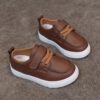 Close up of stylish brown leather boys loafers showcasing the stitching and buckle detail