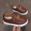 Close up of stylish brown leather boys loafers showcasing the stitching and buckle detail