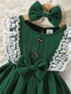 A baby girl wearing a charming summer garden themed dress smiling