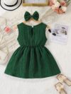 A baby girl wearing a charming summer garden themed dress smiling