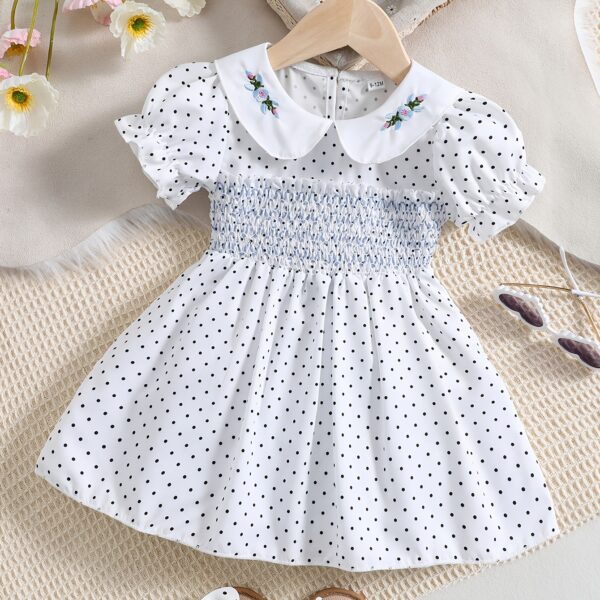 Adorable little girl twirling in a charming summer polka dot dress perfect for birthdays and special occasions