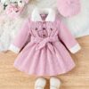 Adorable baby girl wearing a cozy corduroy dress set in fall colors perfect for autumn and winter The outfit includes a dress and matching pants
